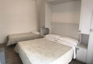 2 letti in una piccola camera con pareti bianche di Hotel Nelson a Rimini