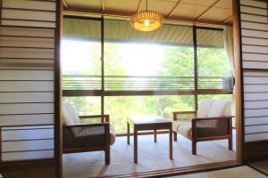 a screened in porch with two chairs and a table at Yoshitagawa Bekkan in Higashine