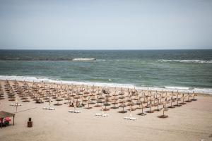 un montón de sombrillas y sillas en una playa en Hotel Megalos, en Constanţa