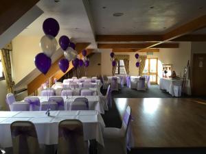 un salón de banquetes con mesas blancas y globos púrpura en The Abbey Hotel and conference centre, en Minster