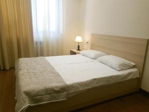 1 dormitorio con 1 cama con sábanas blancas y ventana en M&N apartments en Ereván