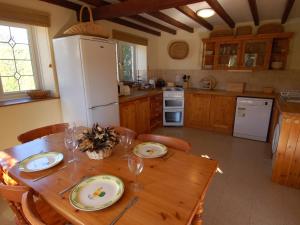 eine Küche mit einem Holztisch und einem weißen Kühlschrank in der Unterkunft Jacobs Barn in Lifton