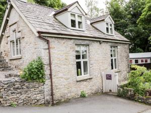 una vecchia casa in pietra con un muro di pietra di Honeypot Cottage a Kendal