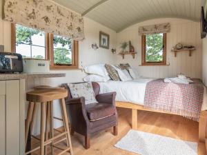 a small bedroom with a bed and a chair at Padarn's Hut in Llanbadarn-fynydd