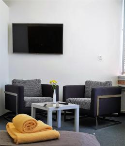 sala de estar con 2 sofás, mesa y TV en CREO Munich City, en Múnich