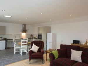 a living room with two chairs and a kitchen at Fritillary Cottage in Bradworthy