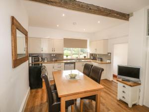 a kitchen with a table and chairs and a television at Farley Cottage I in Oakamoor