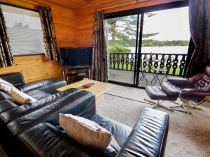 a living room with leather furniture and a large window at Hope Lodge in Carnforth