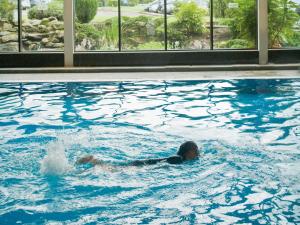 a person in a swimming pool in a building at Macdonald Forest Hills Hotel & Spa in Aberfoyle