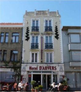 Un bâtiment avec un groupe de gens assis à l'extérieur dans l'établissement Hotel Anvers, à La Panne