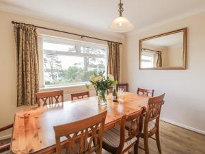 a dining room with a wooden table and a window at Bay View in Benllech