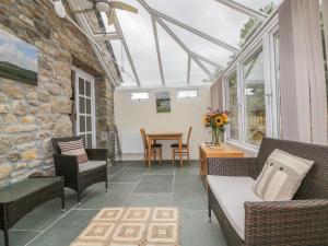 a conservatory with a couch and chairs and a table at The Smithy in Bodmin