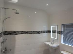 ein weißes Badezimmer mit Waschbecken und Dusche in der Unterkunft Fritillary Cottage in Bradworthy