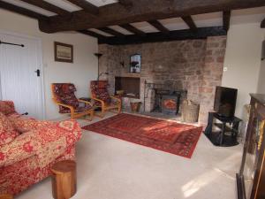 een woonkamer met een bank en een open haard bij Appletree Cottage in Ilsington