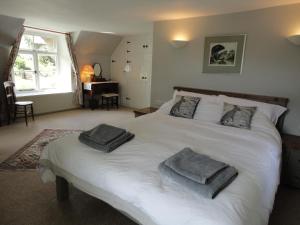 a bedroom with a white bed with two towels on it at Thorn Cottage in Chagford