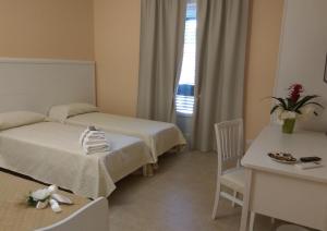 ジノーザ・マリーナにあるLe Camelieのベッド2台とテーブルが備わるホテルルームです。