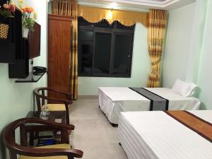 a room with two beds and a tv and a window at Ruby Hostel in Ha Giang