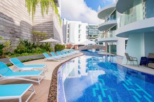 a swimming pool with lounge chairs and a building at APlan Properties in Patong Beach
