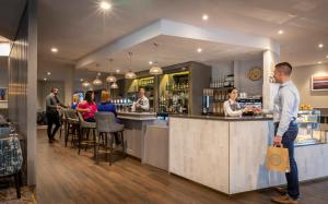 a man standing at a bar in a restaurant at Maldron Hotel Sandy Road Galway in Galway