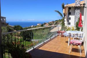 balcón con mesa y vistas al océano en Casa da Fonte dos Castanheiros en Estreito da Calheta