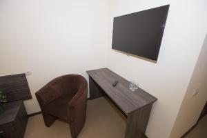 Habitación con mesa, silla y TV. en GagarInn Hotel, en Kazán