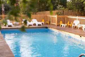 a swimming pool with chairs and a wooden deck at Cabin Resort in Moshav Ramot