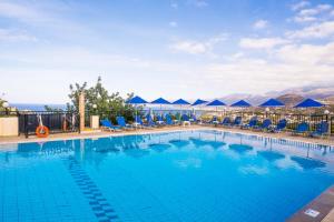 uma grande piscina com cadeiras azuis e montanhas em Mariamare apts em Stalida