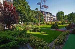 a garden with green grass and bushes and buildings at Rezydencja Familia in Świnoujście