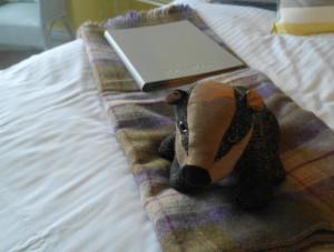 a stuffed animal is sitting on a bed with a laptop at Lulworth Cove Inn in Lulworth Cove