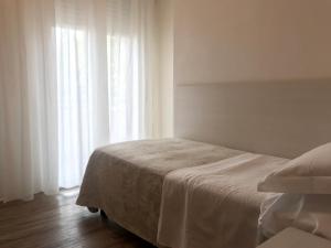 a white bedroom with a bed with white curtains at Hotel Nelson in Rimini