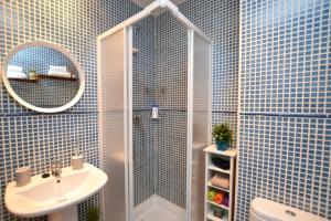 a blue tiled bathroom with a shower and a sink at Ático con terraza en el centro de Alicante in Alicante