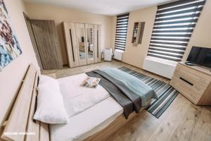 a bedroom with a bed and a tv and windows at Brickyard Apartments Cluj in Cluj-Napoca