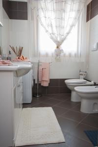 łazienka z umywalką, toaletą i oknem w obiekcie appartamento a cavallino w Cavallino-Treporti
