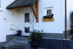una casa blanca con una puerta y flores en una ventana en Ferienwohnung Holterhoff en Olpe