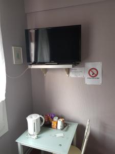 uma mesa com uma televisão numa parede com uma mesa com um sidx de mesa em Hotel des Voyageurs em Mayenne