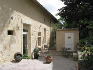 a stone house with a patio and a table and chairs at B&B Les Secrets de Tifayne in Puisseguin