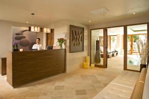 a man sitting at a reception desk in a lobby at Grupotel Los Príncipes & Spa in Playa de Muro