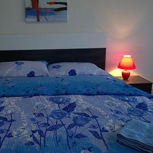 a bed with a blue comforter and a lamp at Felix Apartment in Soko Banja