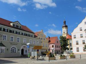 eine Stadtstraße mit Gebäuden und einem Uhrturm in der Unterkunft Hotel Brauereigasthof Amberger in Kösching