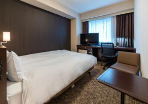 a hotel room with a bed and a desk and a computer at Daiwa Roynet Hotel Nagoya Eki Mae in Nagoya