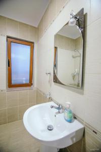 La salle de bains est pourvue d'un lavabo, d'un miroir et d'une fenêtre. dans l'établissement Vila Panorama Voskopoje, à Voskopojë