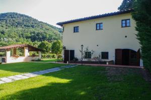 una gran casa blanca con un patio de césped en CASALE LA FATA -tipico toscano immerso nelle colline tra Lucca e Versilia, 6 appartamenti indipendenti, en Camaiore