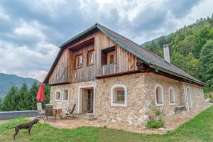 a stone house with a dog standing in front of it at Obiralmhütte Mosgan in Bad Eisenkappel