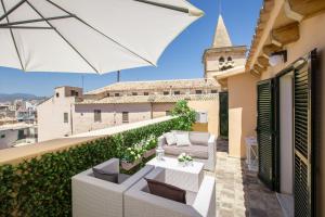 balcón con mesa, sillas y sombrilla en Confraria Singular Suites en Palma de Mallorca