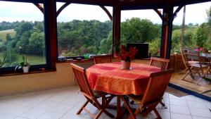 a dining room with a table and chairs and windows at Belle Longère in Campeaux