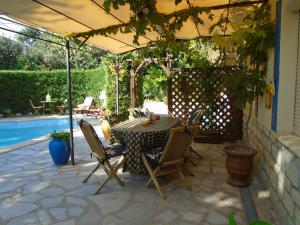 un patio con mesa y sillas junto a una piscina en La Soleillade Laudun en Laudun
