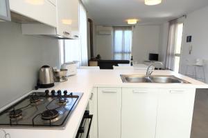 a white kitchen with a stove and a sink at casa verdemare in Cefalù