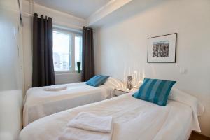 two beds in a room with a window at RovaVisit Apartments Paroni in Rovaniemi