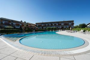 a large swimming pool with chairs and a building at Callas Family Apartment in Sirmione