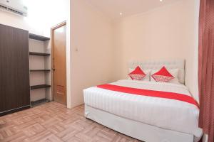 1 dormitorio con 1 cama blanca grande con almohadas rojas en SUPER OYO Capital O 141 Fatmawati Cozy Residence, en Yakarta